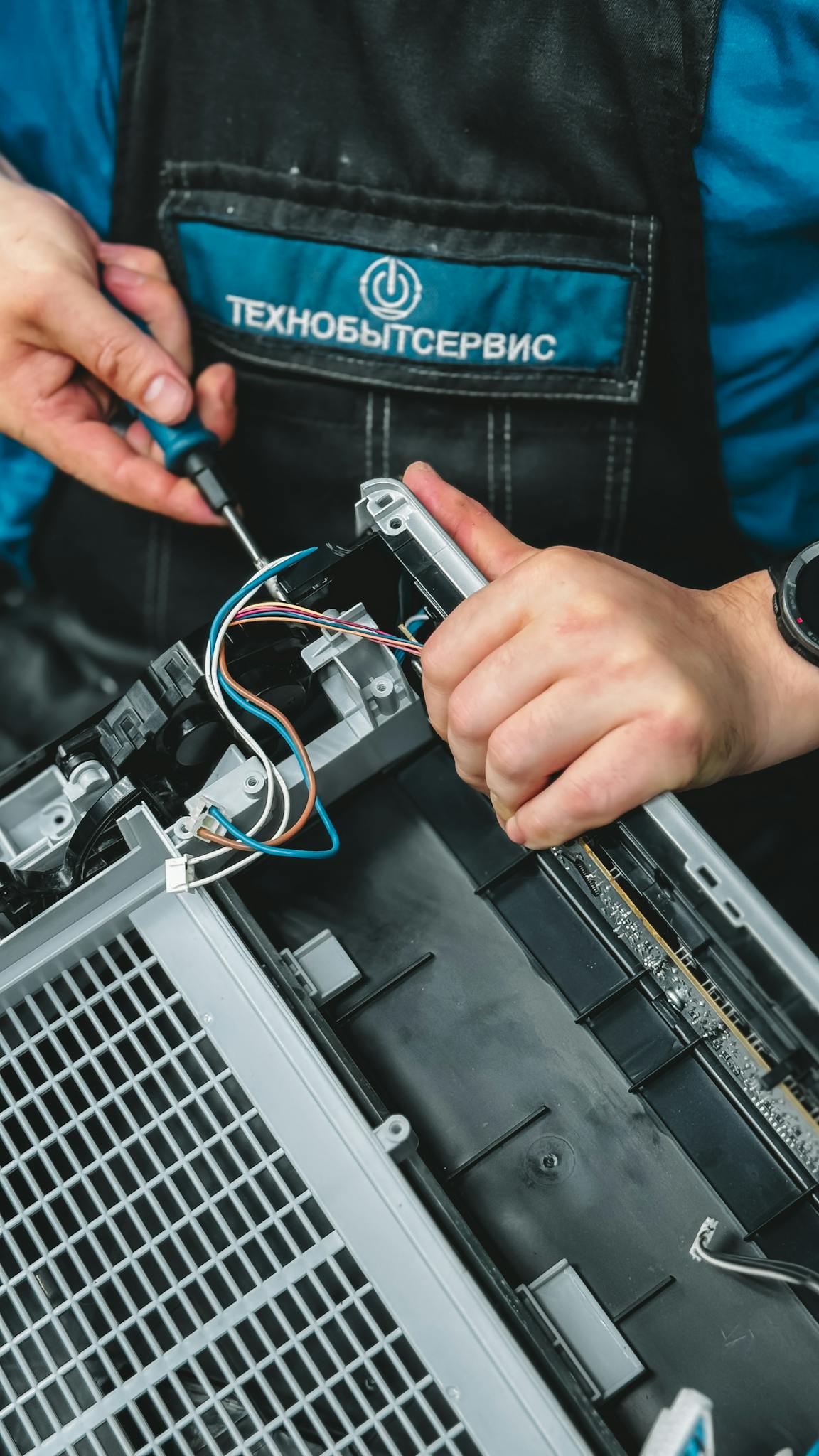 Close-up of technician repairing a device, showcasing wiring and tools, ideal for tech and repair themes.